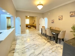 A modern interior with a marble floor, a dining area with chairs, and a chandelier. - 3BRs Garden City Lexus Living (Cairo Governorate)
