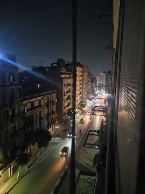 A nighttime cityscape viewed from a window, featuring a street with vehicles and illuminated buildings. - 3BRs Garden City Lexus Living (Cairo Governorate)