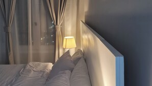 Een hotelkamer met een bed, een bedlampje en dunne gordijnen.
