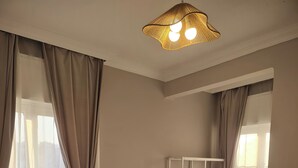 Een hotelkamer met twee bedden, een stapelbed, een vloerkleed met dessin en een hanglamp.
