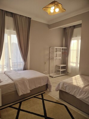 A hotel room with two beds, a bunk bed, a patterned rug, and a hanging light fixture. - 3BRs Garden City Lexus Living (Cairo Governorate)