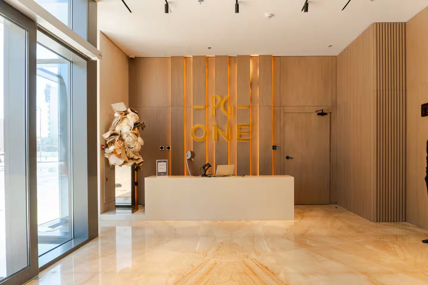 A modern reception area with a reception desk, a large window, and a decorative floral arrangement.