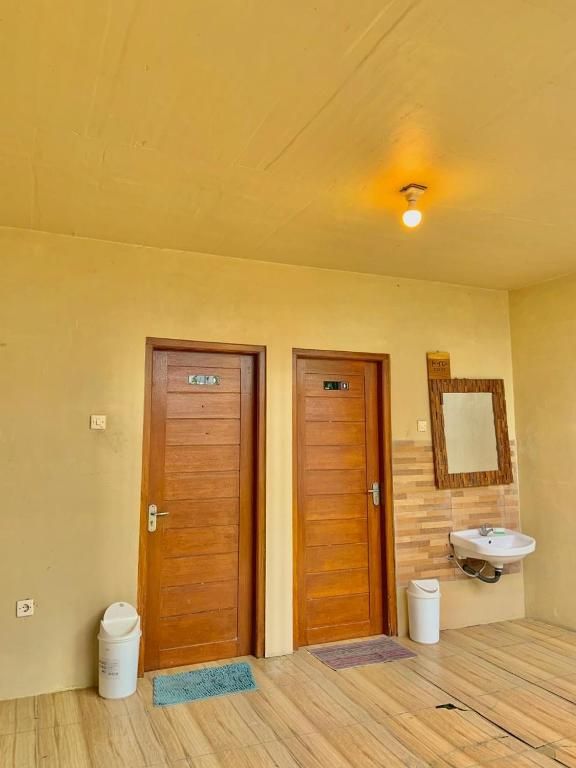 A room with two wooden doors, a sink, and a mirror on the wall.