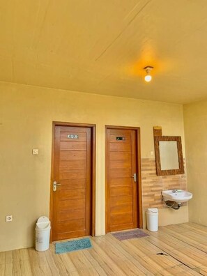 Una habitación con dos puertas de madera, un lavamanos y un espejo en la pared.