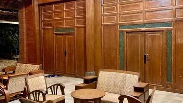 Un área de estar exterior con mobiliario de madera y piso de baldosas.