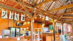 A rustic interior with exposed wooden beams, a brick wall, a counter with stools, and a shelf with various items. - Sokkyo Homestay Kaliurang (DI Yogyakarta)