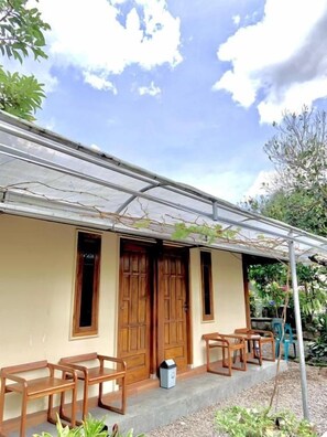A single-story building with a covered porch, wooden doors, and a row of chairs. - Sokkyo Homestay Kaliurang (DI Yogyakarta)