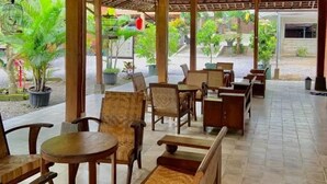 An outdoor seating area with wooden furniture and a thatched roof structure. - Sokkyo Homestay Kaliurang (DI Yogyakarta)