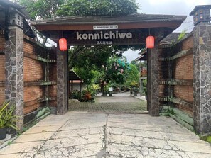 Un torii tradicional japonés con estructura de piedra y madera, un letrero encima y un acceso pavimentado.