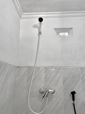 A shower with a handheld showerhead and a wall-mounted faucet. - Sokkyo Homestay Kaliurang (DI Yogyakarta)