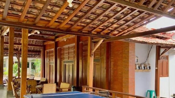 A covered outdoor area with a ping pong table, wooden beams, and a tiled floor. - Sokkyo Homestay Kaliurang (DI Yogyakarta)