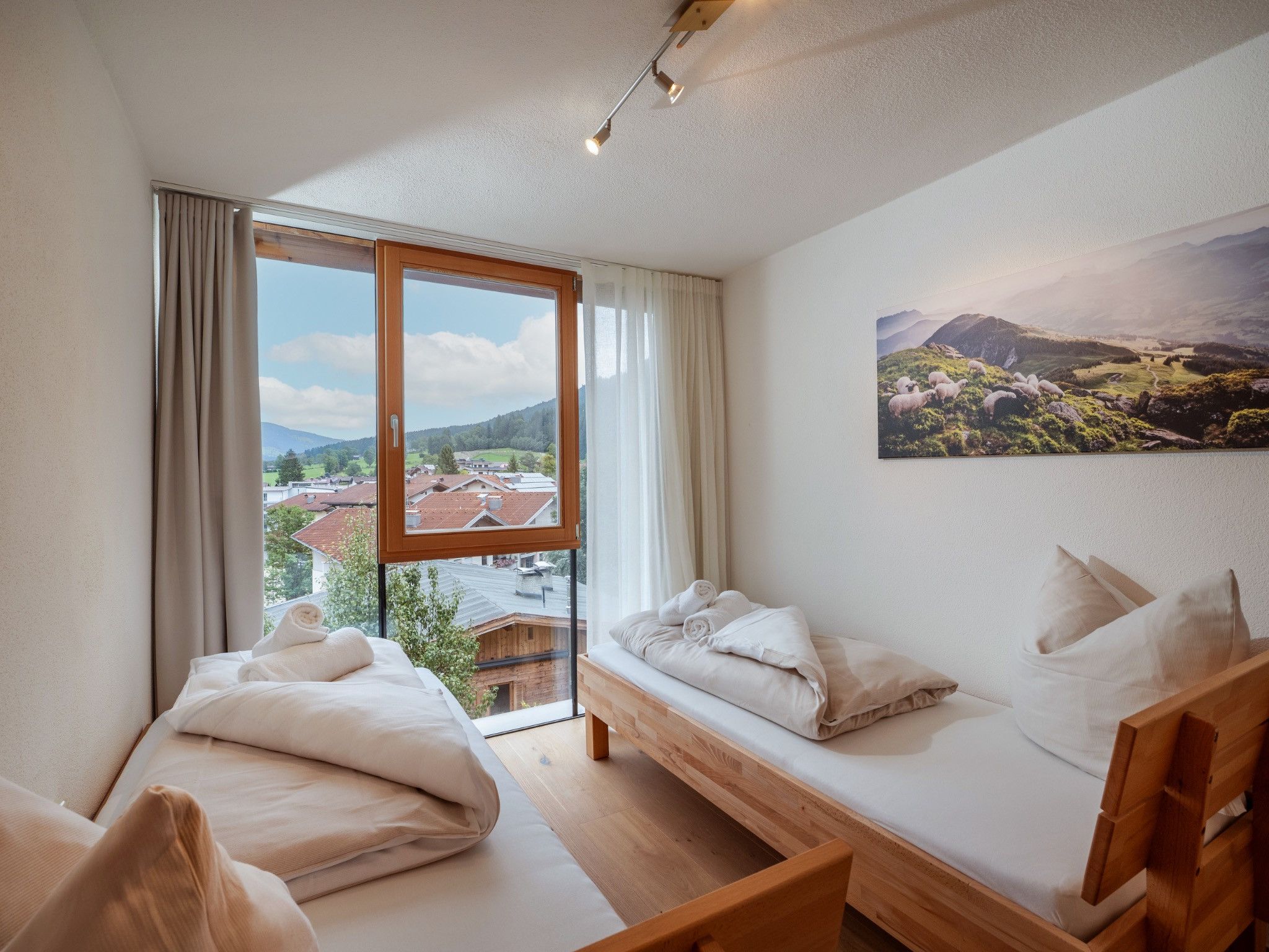 Ein Schlafzimmer mit großem Fenster, einem Bett, einer Couch und einem Landschaftsbild.