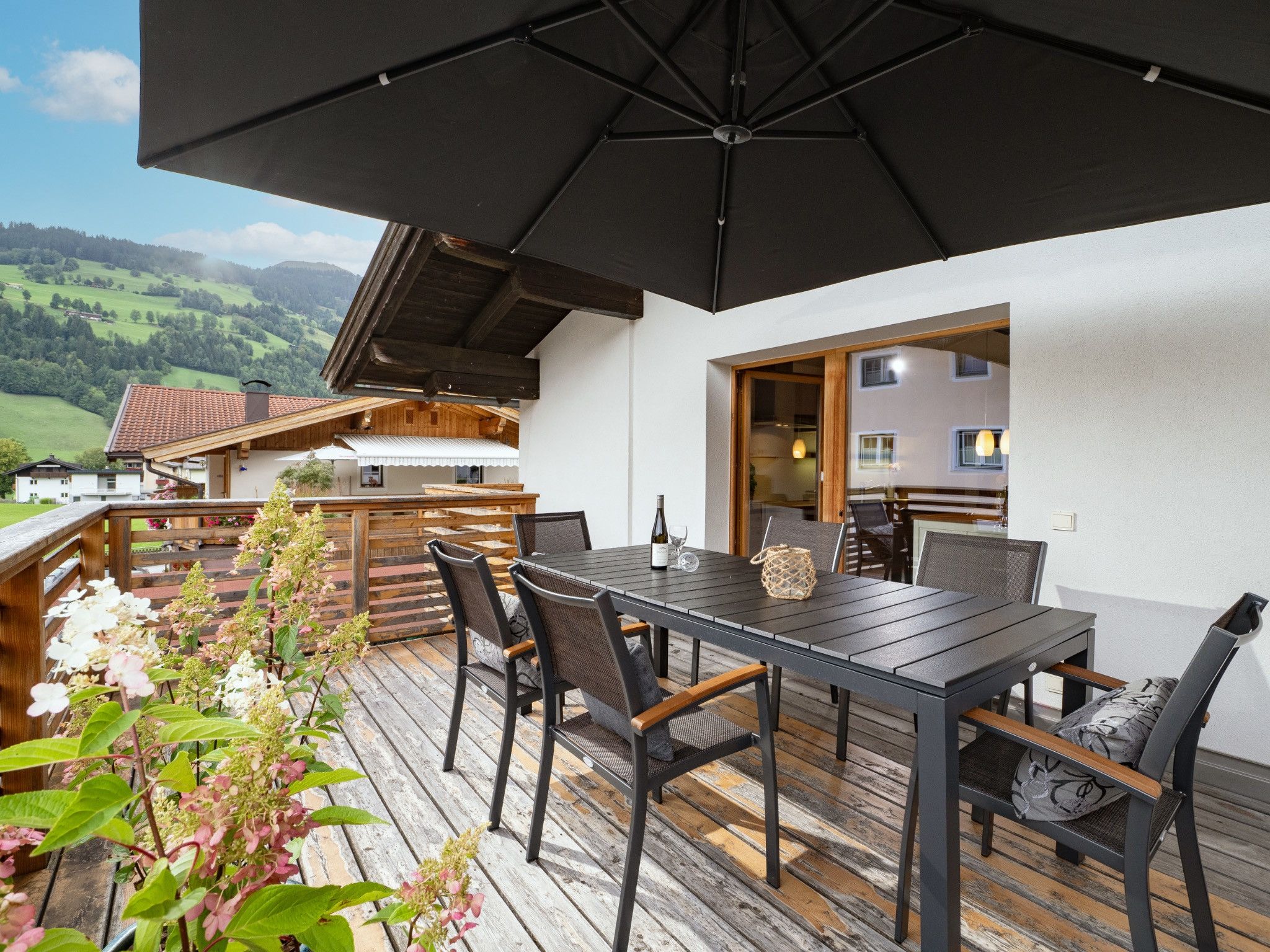 Un espace extérieur aménagé pour les repas, avec une table et des chaises, un grand parasol et une vue sur le paysage environnant.