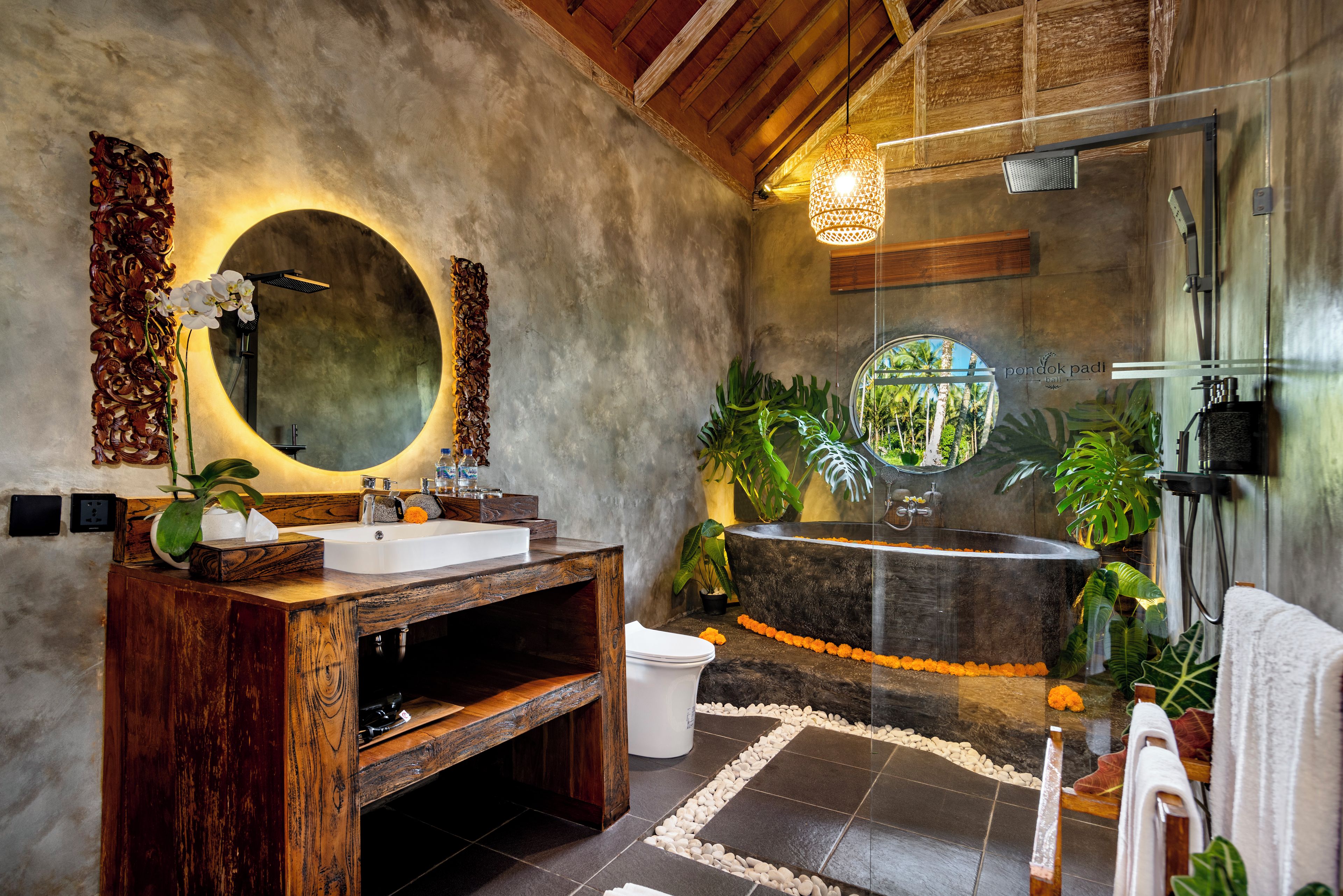 Une salle de bain avec un meuble-lavabo en bois, un miroir rond, une baignoire sur pieds et un espace douche.