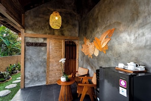 A modern interior with a wooden door, a table with a vase of flowers, and a decorative wall piece. - Pondok Padi Bali Villa (Taro)