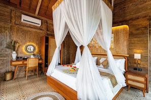 A room with a four-poster bed, a desk with a chair, a wall-mounted air conditioner, and a woven basket. - Pondok Padi Bali Villa (Taro)