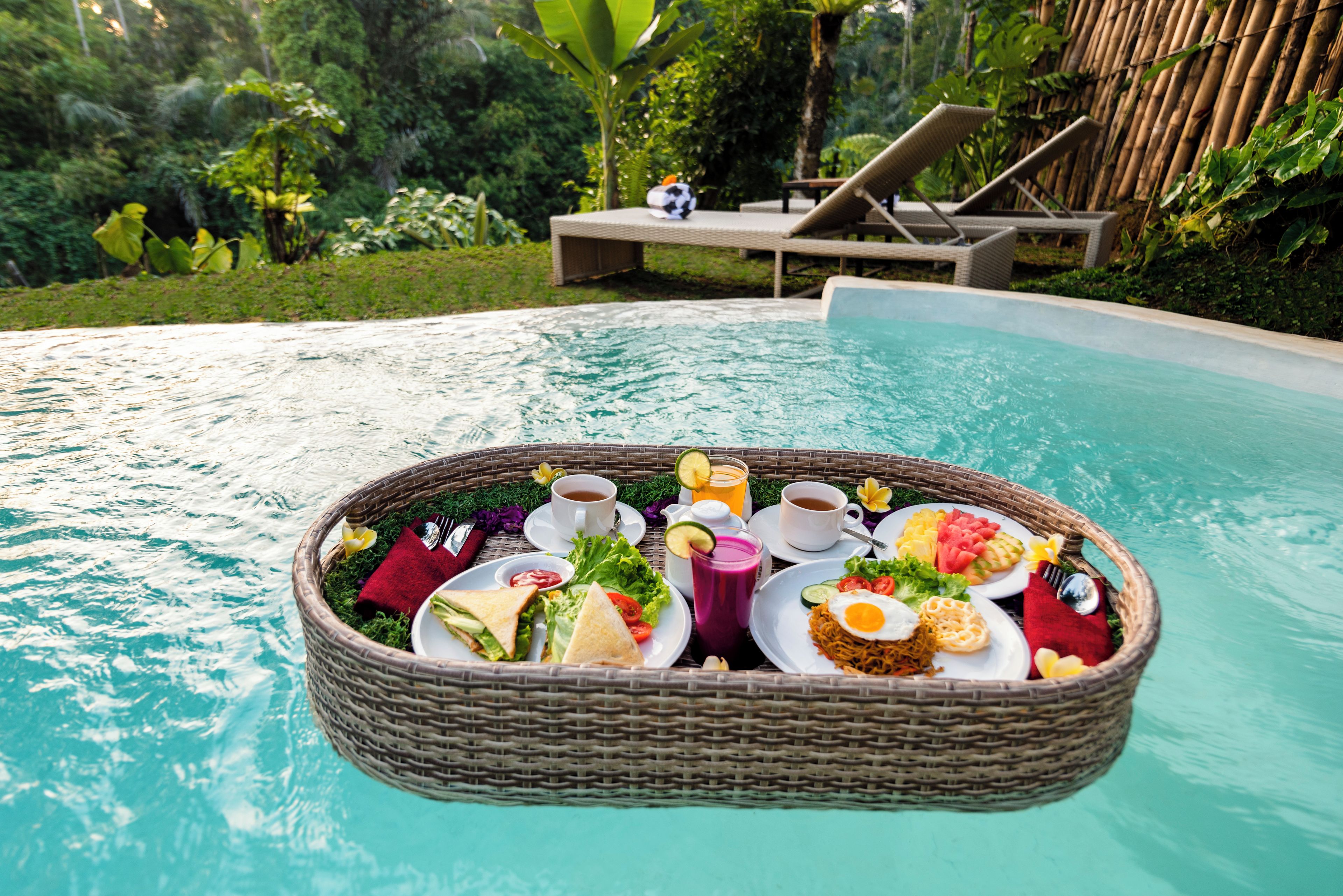 Desayuno flotante con una variedad de comida y bebidas junto a una piscina.