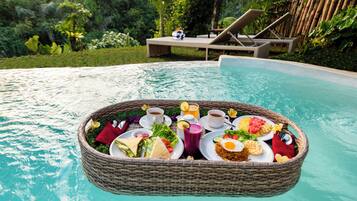 Desayuno flotante con una variedad de comida y bebidas junto a una piscina.