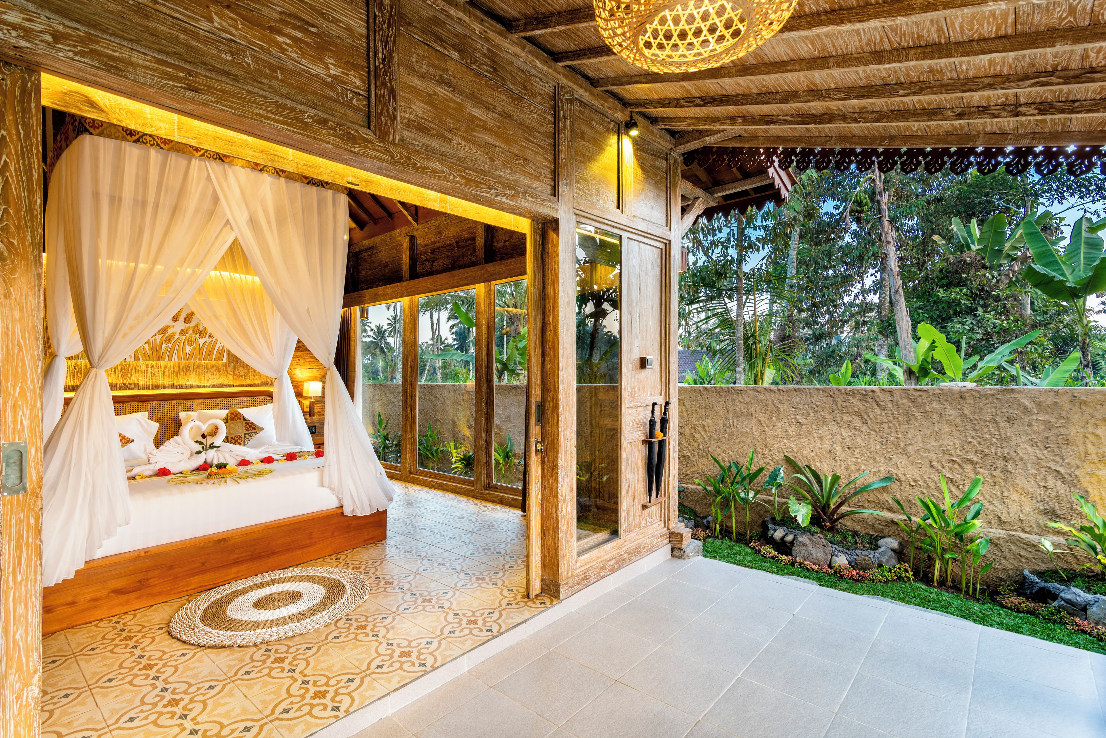 A room with a bed, a canopy, and a view of the garden.