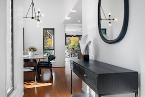 A modern interior with a dining area, a dark wooden console, and a large mirror. - KARINYA LODGE - The Vintage Holiday Houses (POKOLBIN)