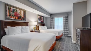 Une chambre d’hôtel avec deux lits, une télévision, un bureau et une commode.