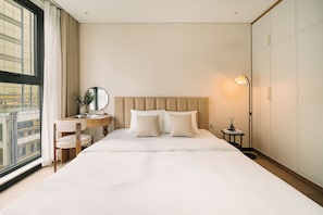 A hotel room with a large bed, a bedside table with a lamp, a window with curtains, and a view of buildings outside. - The Nelson Luxury Apartment 3Bedroom - FREE Pool, Gym & Sauna (Hà Nội)
