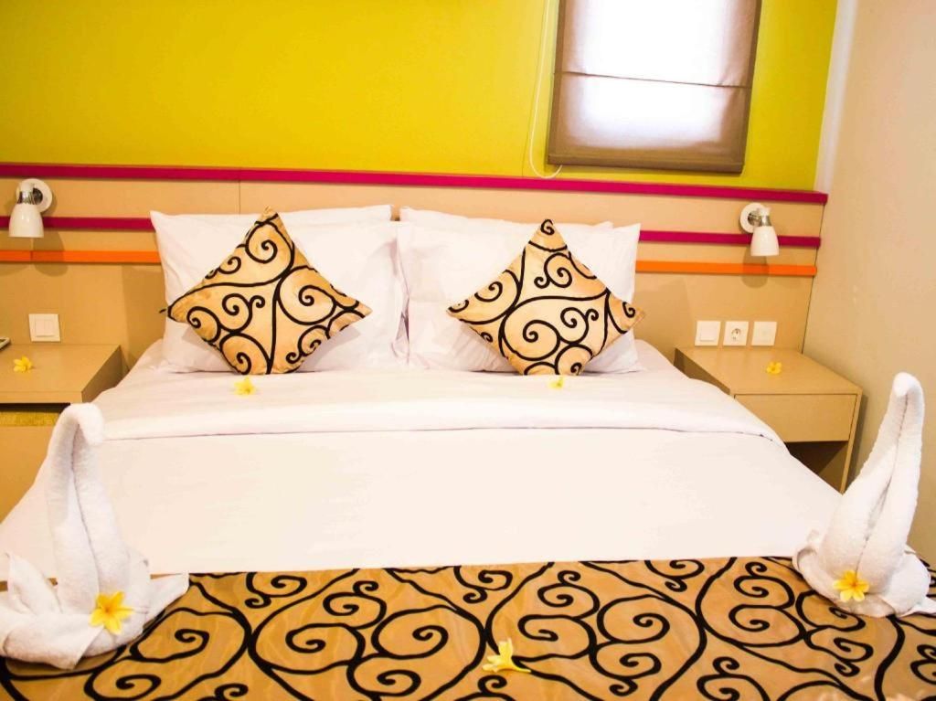 Une chambre d’hôtel avec un lit, des oreillers et une serviette sur le sol.