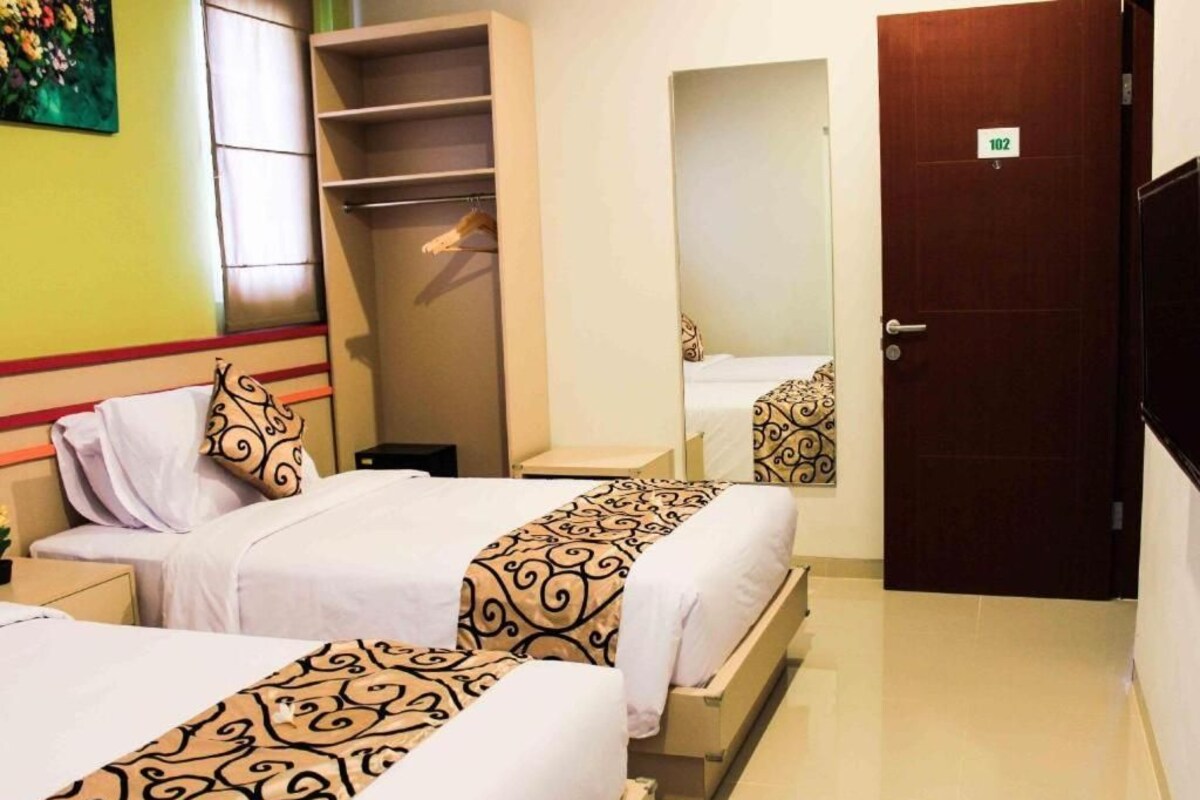 Habitación de hotel con dos camas, un armario, un espejo y una puerta.