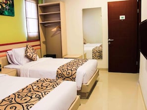 Habitación de hotel con dos camas, un armario, un espejo y una puerta.