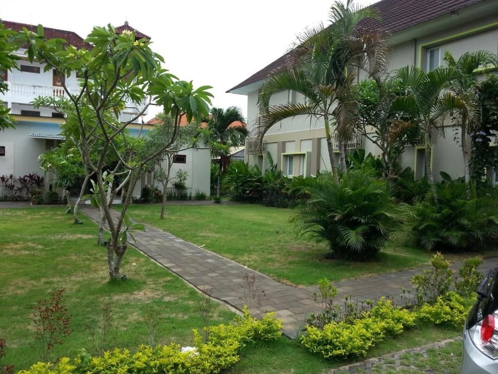 Un quartier résidentiel doté d’un chemin pavé, d’une pelouse verdoyante et de diverses plantes.