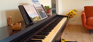 A piano with sheet music, a potted plant, and a chair in a room with wooden flooring. - Country House 'Your Riverside Mill' with Private Terrace, Private Garden and Wi-Fi (Saint-Priest-sous-Aixe)