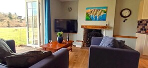 A living room with a fireplace, a television, and a view of the outdoors. - Country House 'Your Riverside Mill' with Private Terrace, Private Garden and Wi-Fi (Saint-Priest-sous-Aixe)