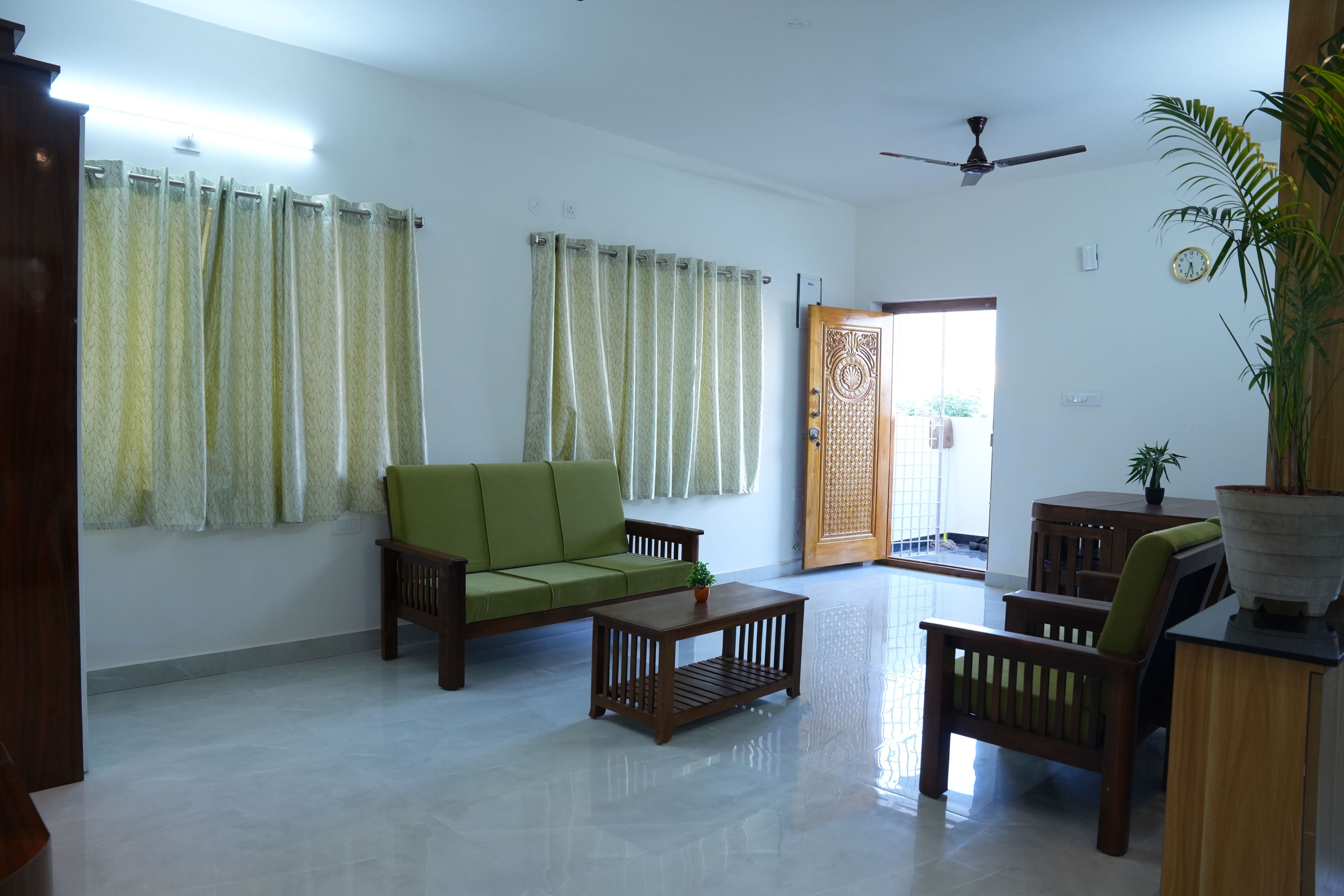 A living room with a sofa, armchair, coffee table, and a potted plant.