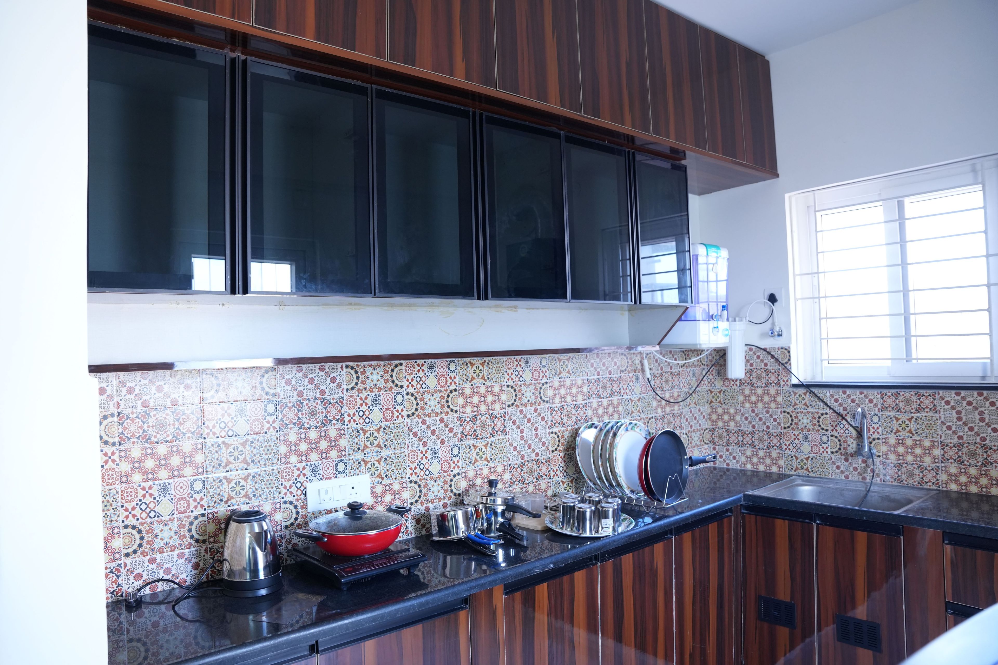 A kitchen with wooden cabinets, a tiled backsplash, and a window with blinds.