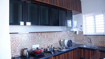A kitchen with wooden cabinets, a tiled backsplash, and a window with blinds.
