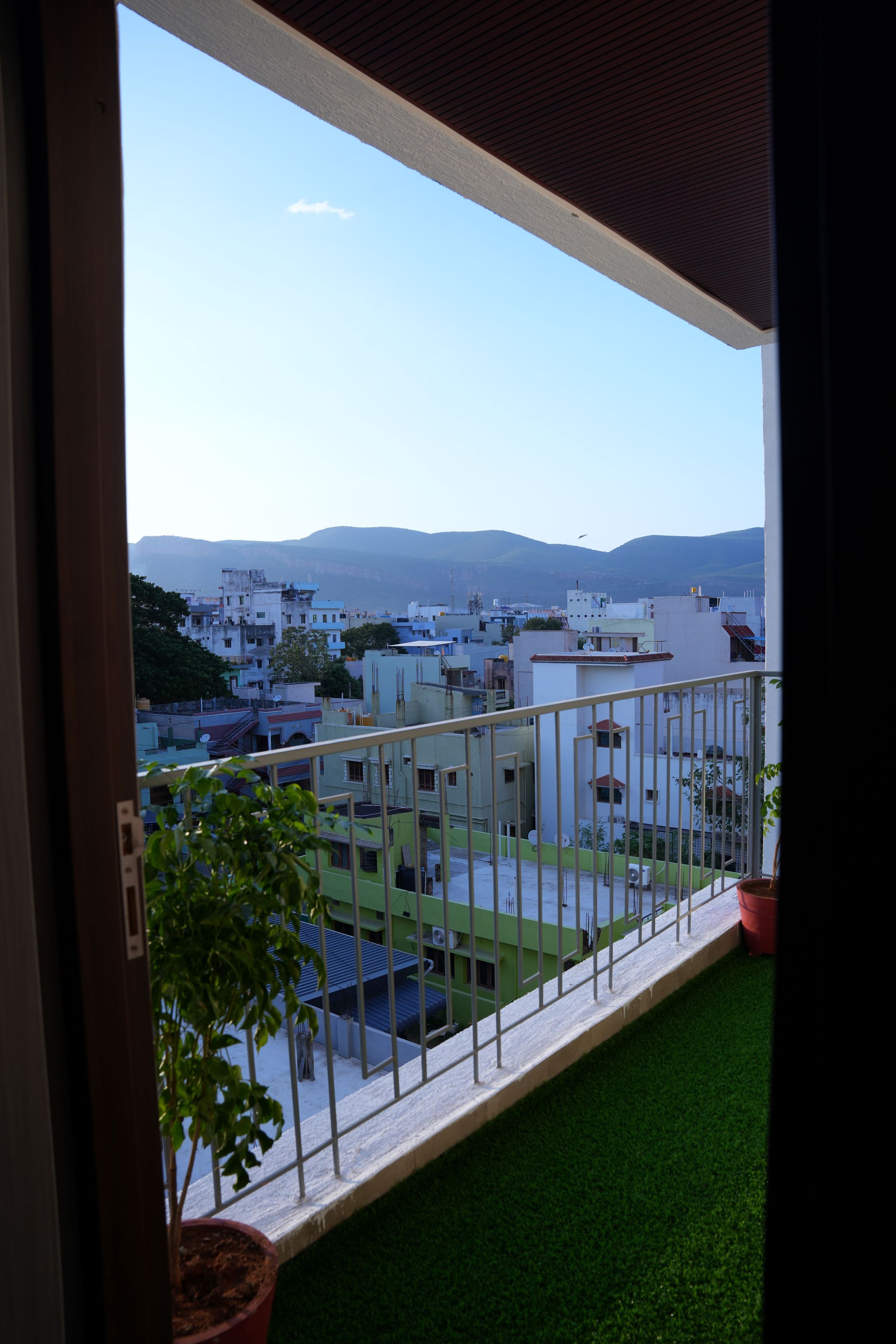 A balcony with a view of a residential area and distant mountains.