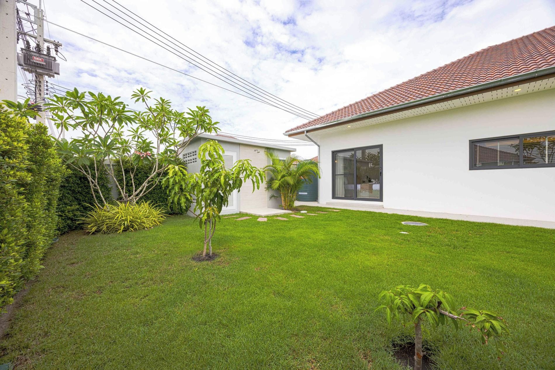 A modern house with a well-maintained lawn, a small tree, and a utility pole with wires.