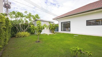 A modern house with a well-maintained lawn, a small tree, and a utility pole with wires.