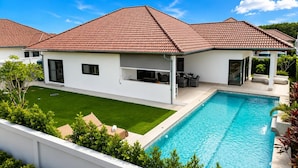 A modern house with a swimming pool, a covered patio, and a well-maintained lawn. - Modern 3BR Villa w/ Private Pool (MV55) (Hua Hin)