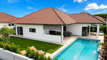 Une maison moderne dotée d’une piscine, d’un patio couvert et d’une pelouse bien entretenue.