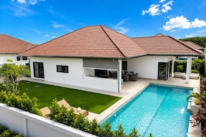 A modern house with a swimming pool, a covered patio, and a well-maintained lawn. - Modern 3BR Villa w/ Private Pool (MV55) (Hua Hin)