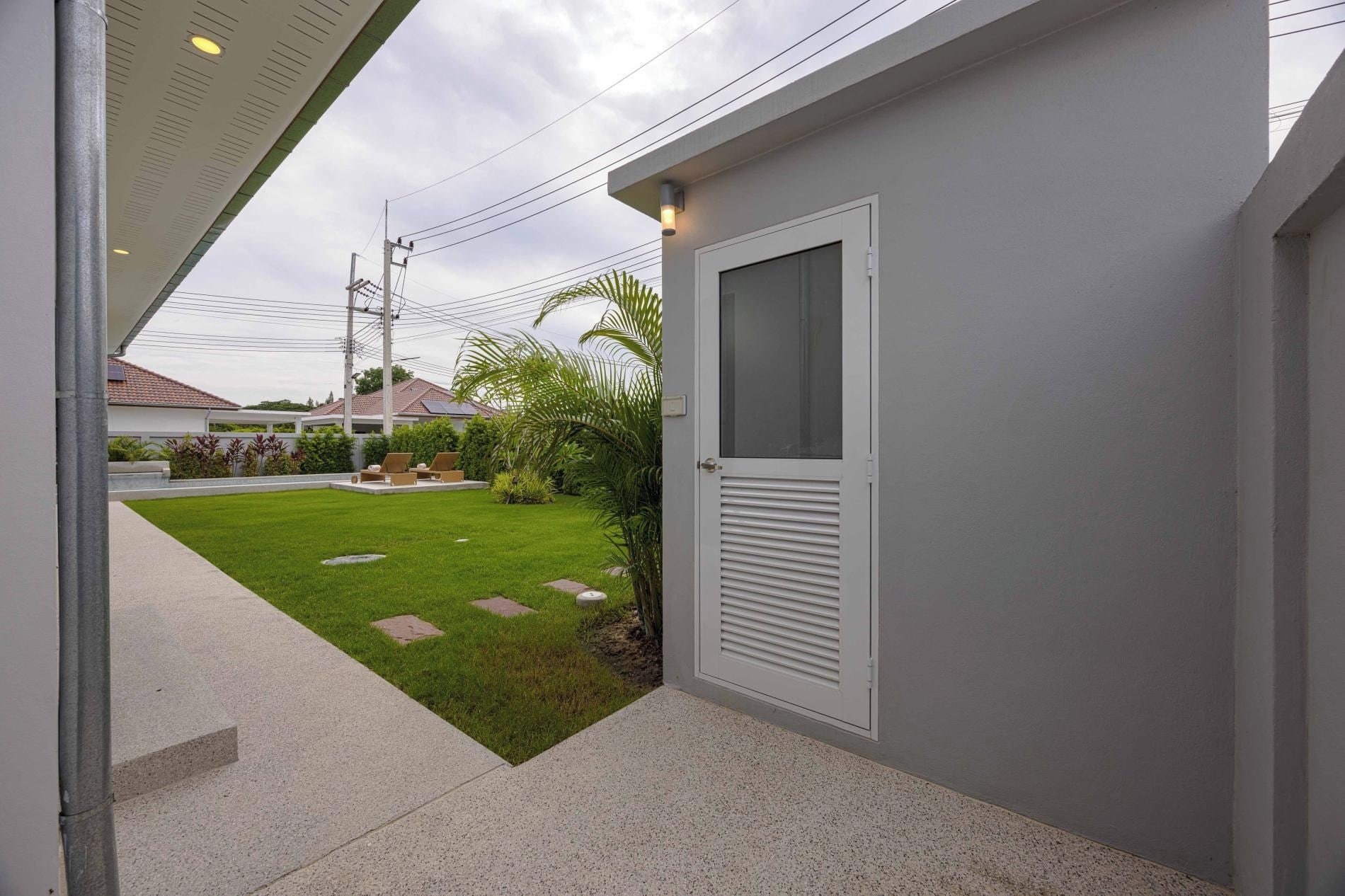 A residential property with a paved entrance, a small lawn, and a door with a window.
