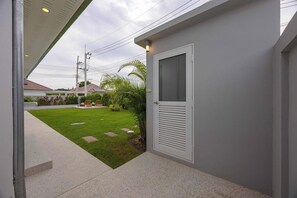 Un inmueble residencial con entrada pavimentada, un pequeño jardín y una puerta con ventanal.