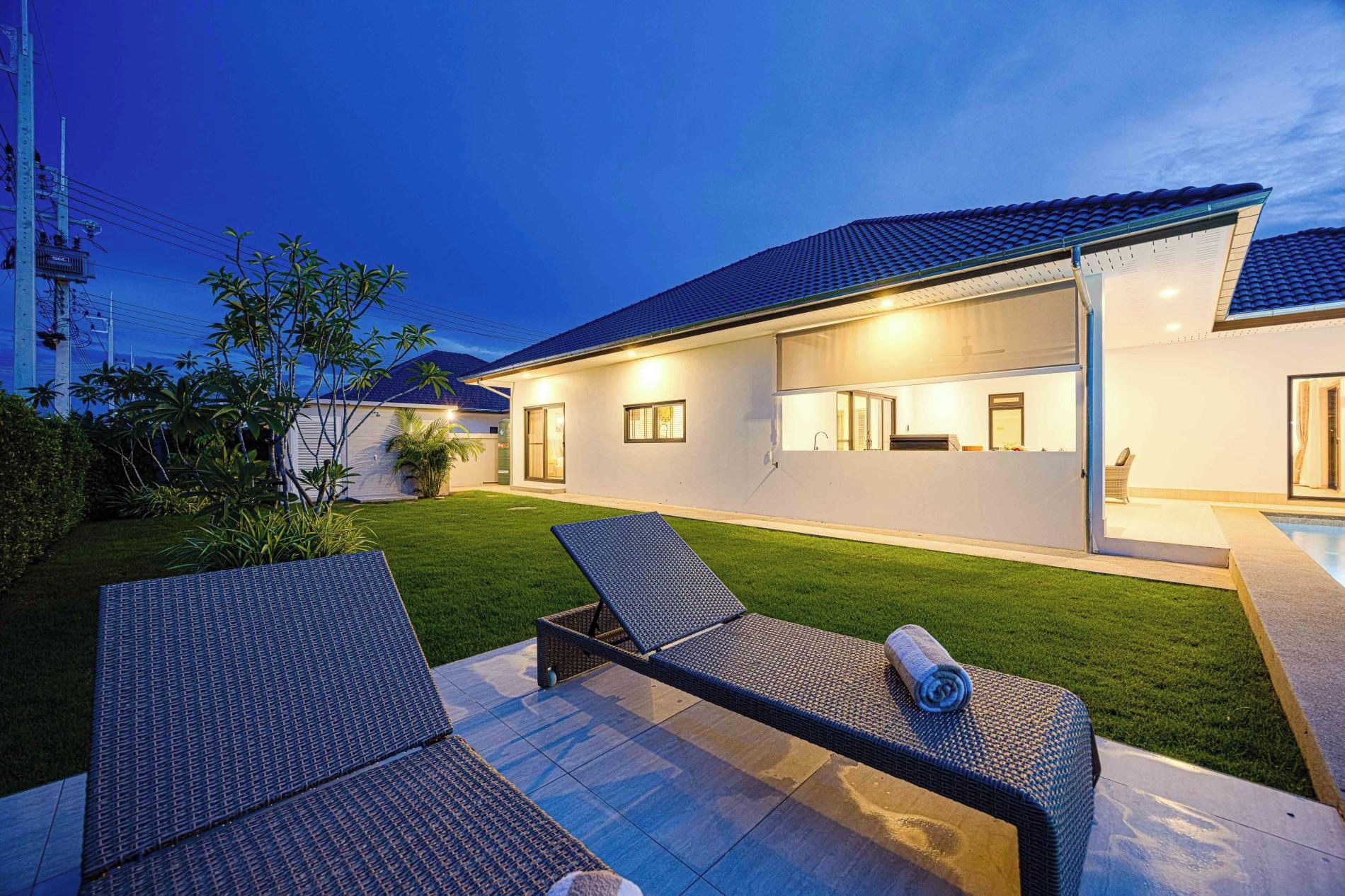 A modern house with a covered outdoor area, a swimming pool, and a well-maintained lawn.