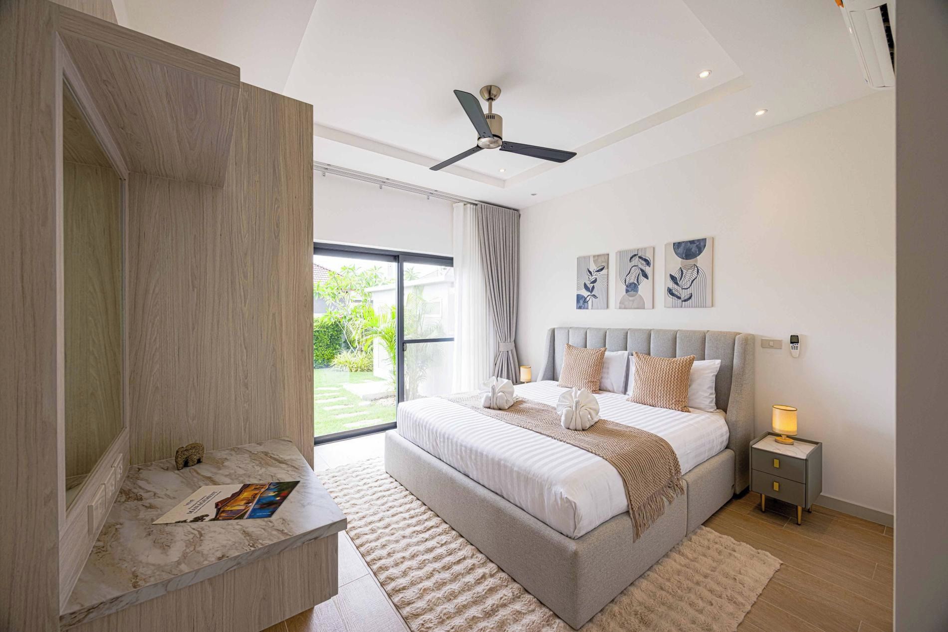 A modern bedroom with a large bed, a ceiling fan, and a view of the outdoors.