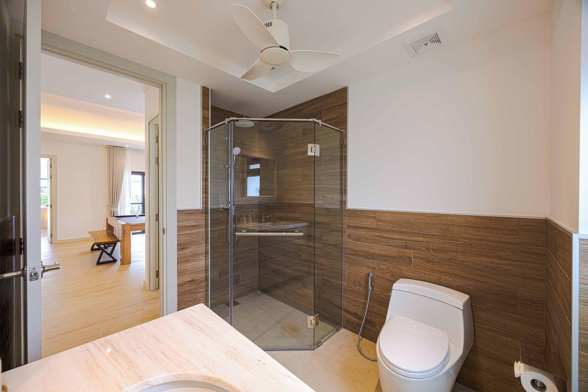 Un baño moderno con ducha envuelta en vidrio, inodoro y tocador con encimera de mármol.