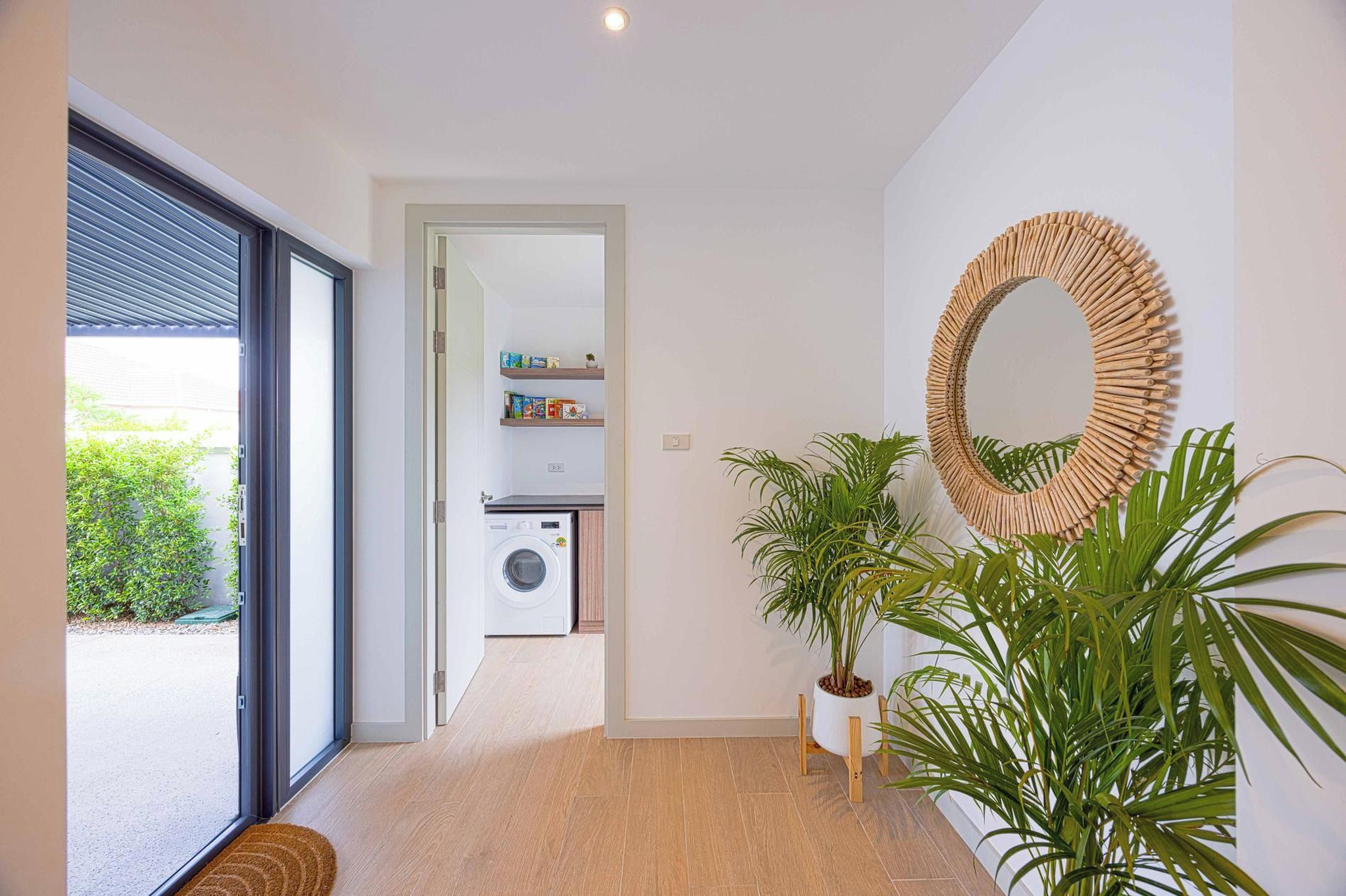 Un intérieur moderne avec un lave-linge, un miroir et des plantes en pot.
