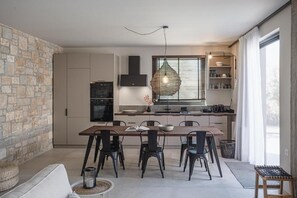A modern kitchen with a dining area, stone wall, and large window.