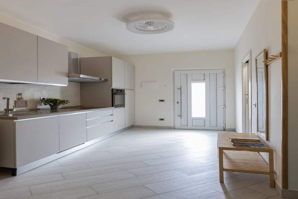 A modern kitchen with white cabinetry, a built-in oven, and a wooden bench.