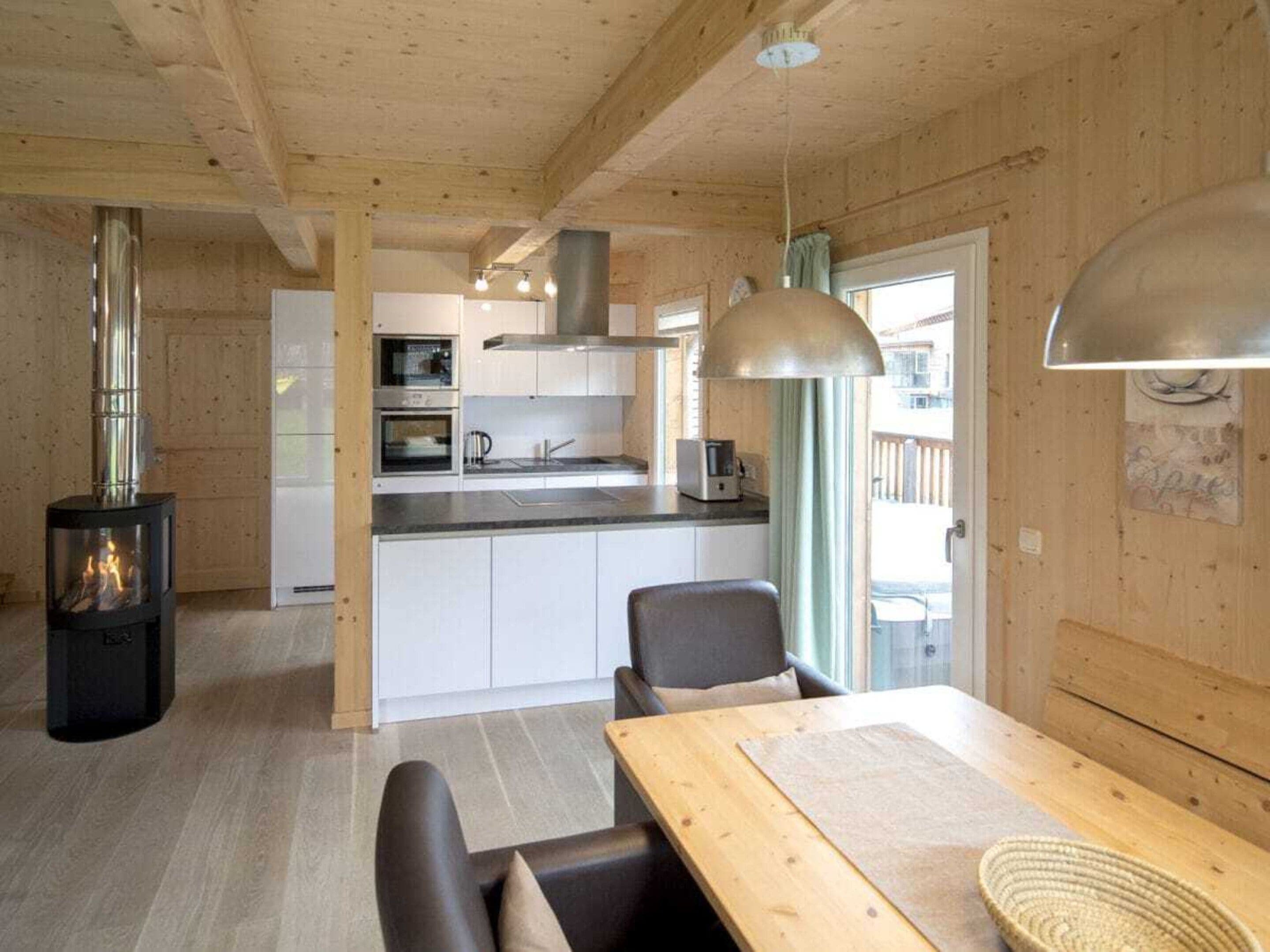 A modern kitchen with white cabinets, a stove, and a dining area with a table and chairs.